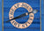 a painted blue wooden board with Cheap Joes Art Stuff in a tan circle and a stylized paint brush through the circle