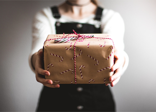 Person holding a Christmas Present (Photo by Kira auf der Heide)